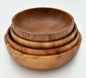 Hand carved acacia bowls stacked together, showcasing the unique wood grain and rich tones of each handcrafted bowl.